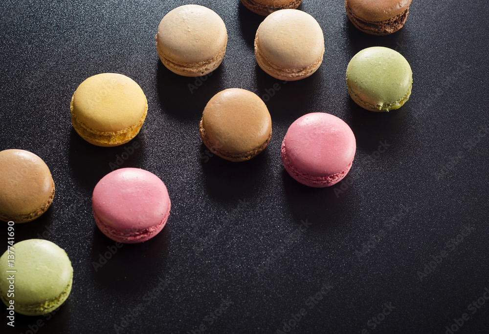Obraz premium Colorful assorted french macaroons on a dark background.