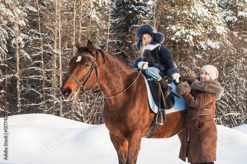Small girl and mom near horse in a winter © keleny