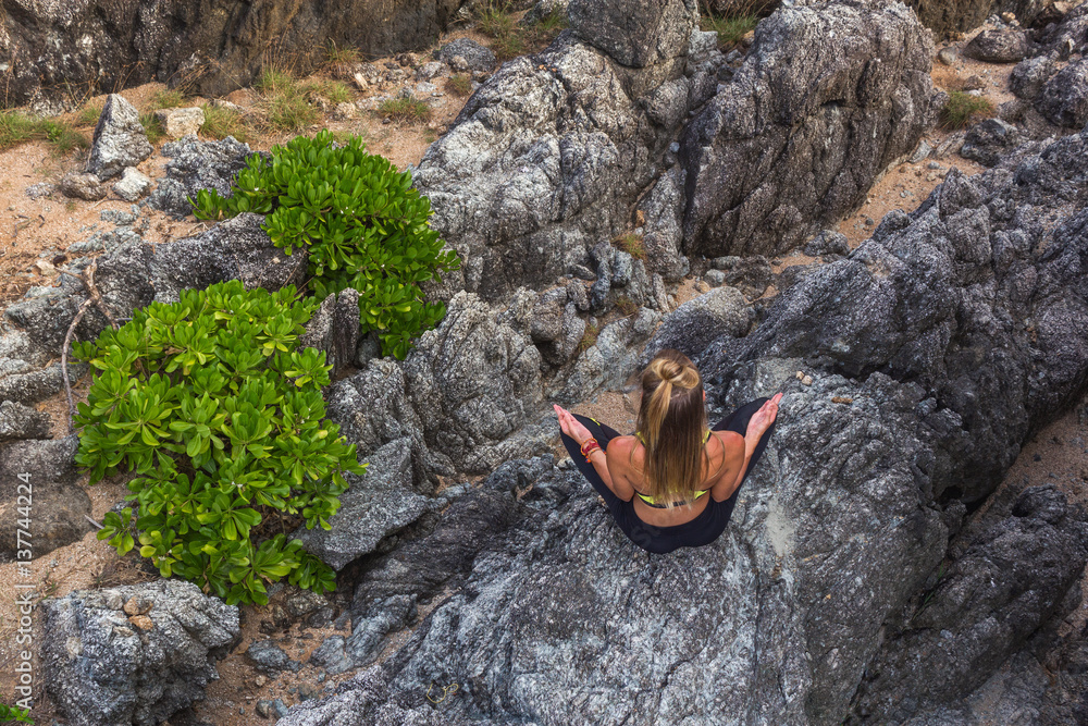 Woman meditating at the cliff. Horizontal shot from above of young woman sitting and meditating in the mountains. Woman meditating at the cliff. Horizontal shot from above of young woman sitting and meditating in the mountains.