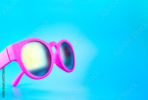 shocking pink color sunglasses at light blue studio background,Summer Holiday concept.Leave space for adding text