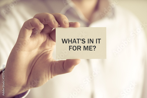 Businessman holding WHATS IN IT FOR ME ? message card