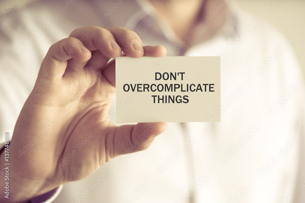 Businessman holding DONT OVERCOMPLICATE THINGS message card