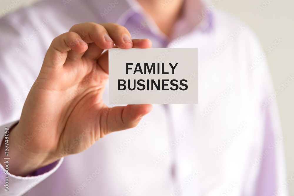 Businessman holding card with text FAMILY BUSINESS Businessman holding card with text FAMILY BUSINESS