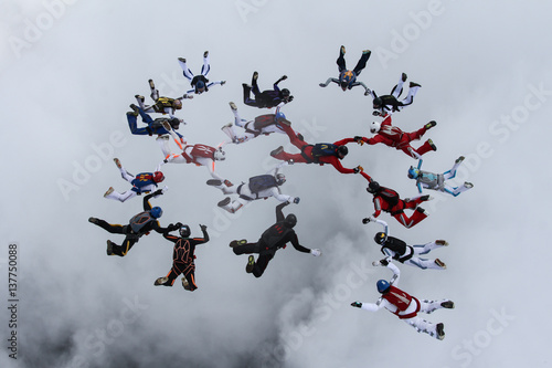 The group of skydivers is falling above the clouds.