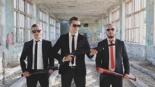 three mens with weapons in abandoned building