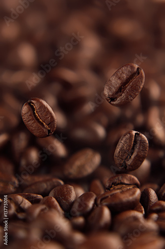 Falling coffee bean on background of heap of roasted beans.