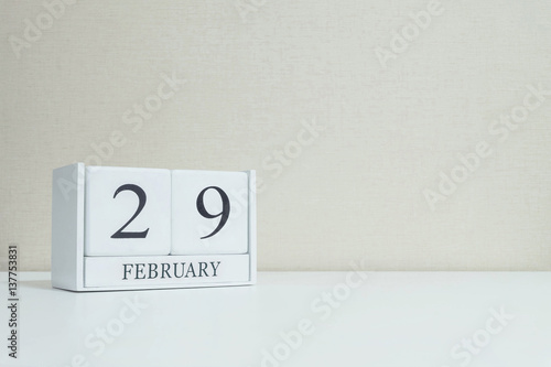 Closeup white wooden calendar with black 29 february word on blurred white wood desk and cream color wallpaper in room textured background with copy space in selective focus at the calendar