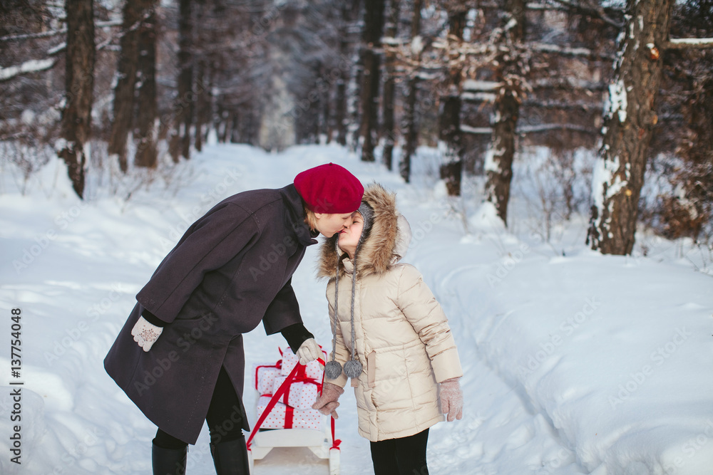 Mother and Daughter Walk and kisses in the Winter Woods With Sledges With Gifts