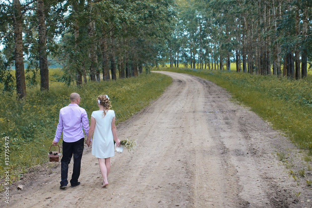 Just married lovers walking in a field in autumn day