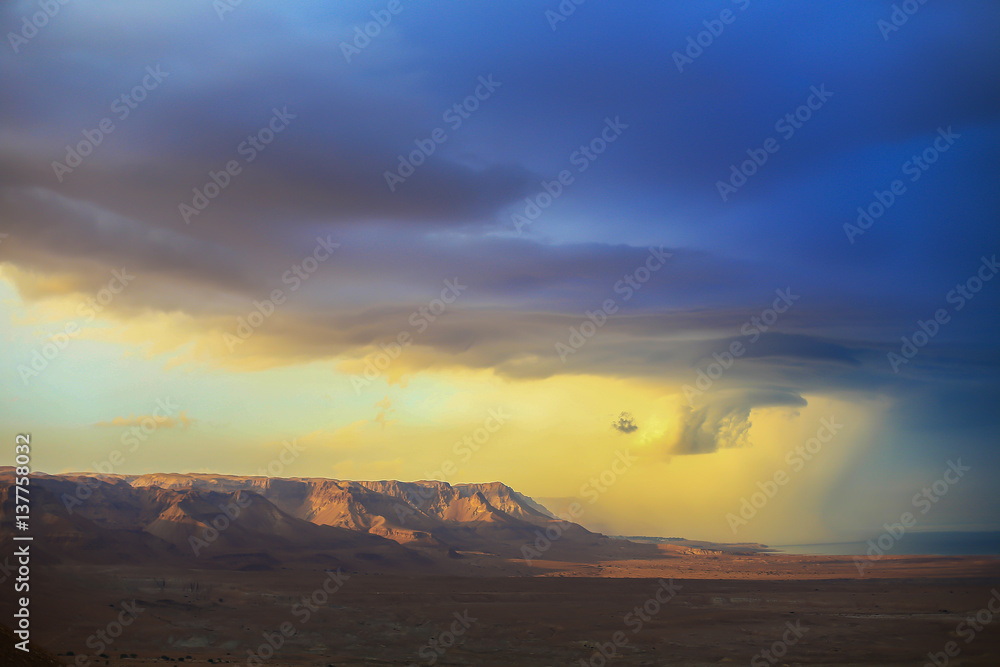 The storm over mountain Masada in Israel. The dramatic landscape, dark blue sky above the mountain. 