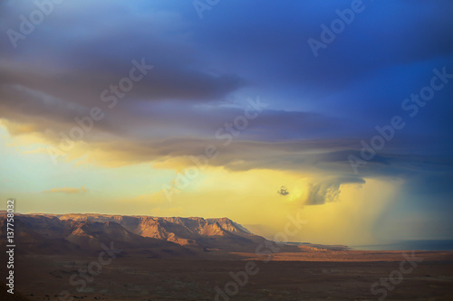 The storm over mountain Masada in Israel. The dramatic landscape, dark blue sky above the mountain. 