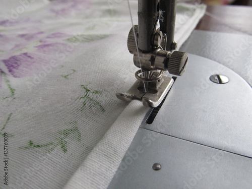 Obraz na plátně Close up detail of a sewing machine needle and the hemmed edge of white fabric