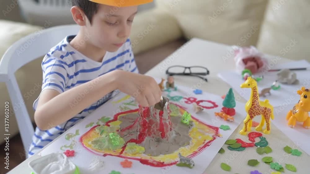 Boy experimenting with clay volcano.The boy is a creative game with volcanoes Boy experimenting with clay volcano.The boy is a creative game with volcanoes