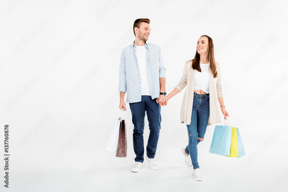 Happy young couple walking with shopping bags and looking at each other Happy young couple walking with shopping bags and looking at each other