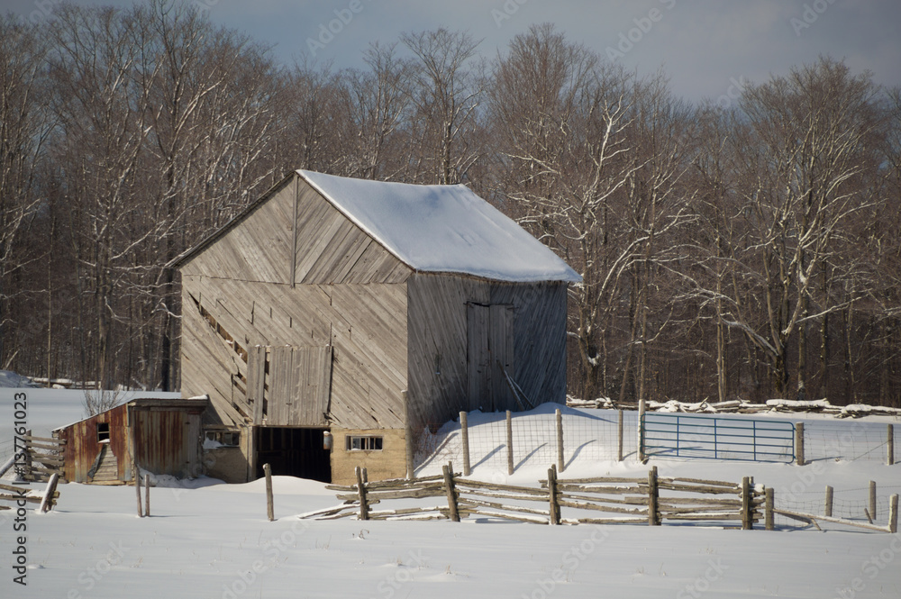 Snowy old  barn with diagonal boards and barnyard