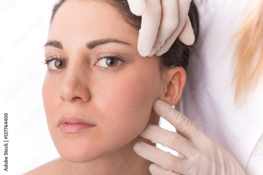 Beauty treatment of the young beautiful female face, doctor's hand in gloves touch face of beautiful young woman isolated on white. Beauty treatment of the young beautiful female face, doctor's hand in gloves touch face of beautiful young woman isolated on white.