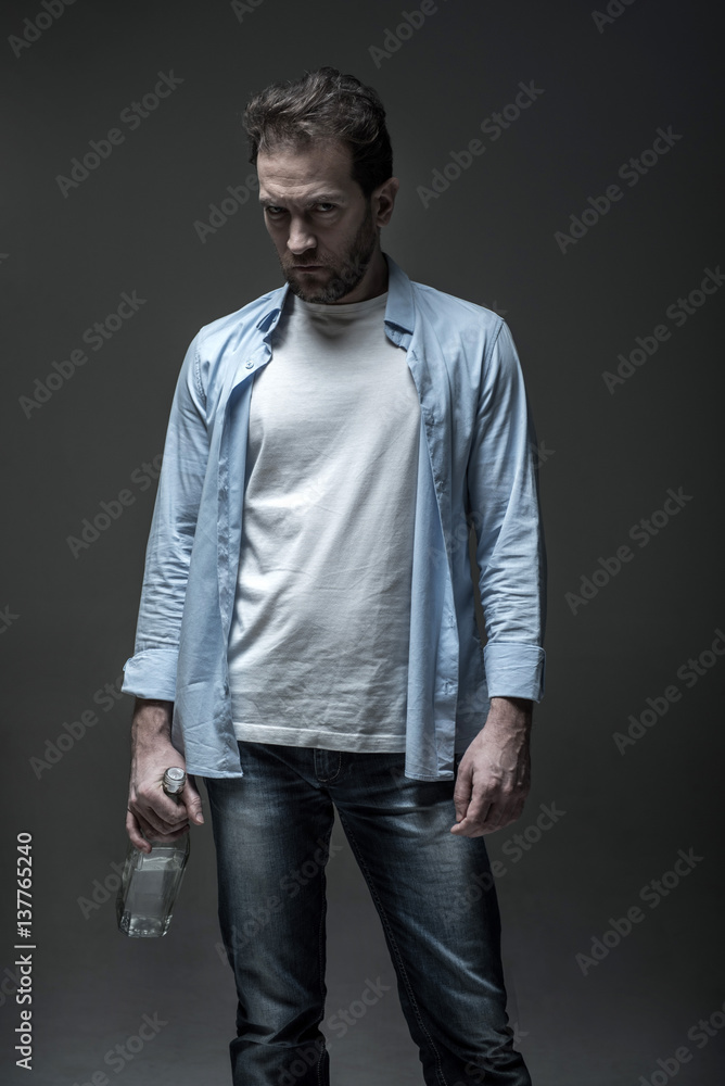 Portrait of severe male person keeping glass bottle Portrait of severe male person keeping glass bottle