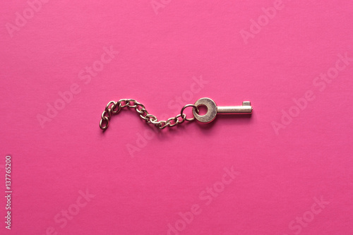 Golden key on a pink background.