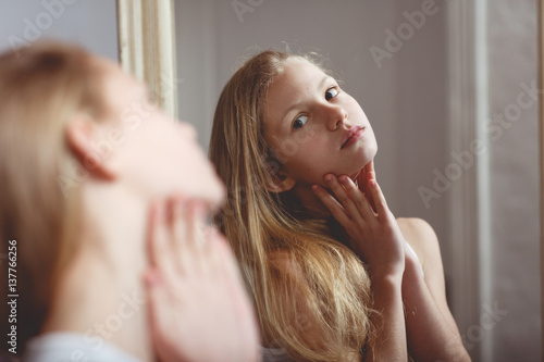 Billede på lærred Teenage girl checking her face and body in the mirror