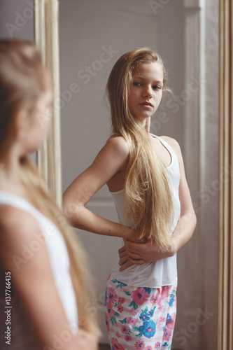 Teenage girl checking her face and body in the mirror