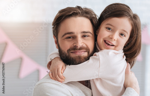 Delighted cute girl embracing her dad