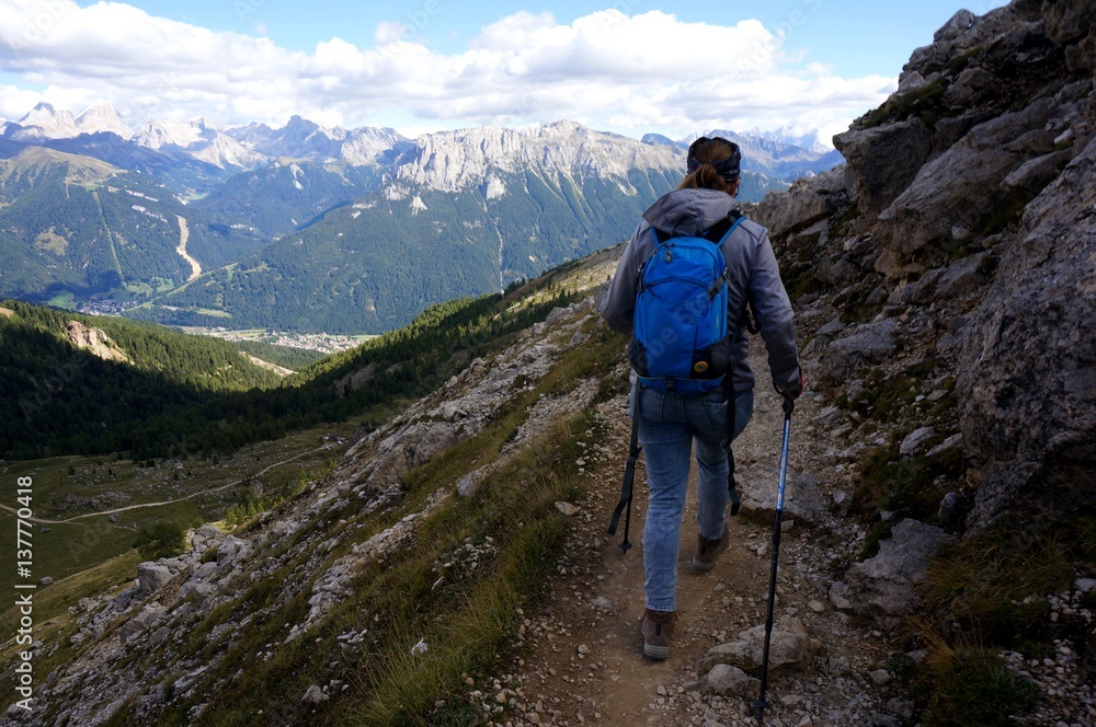 Wanderin alleine unterwegs mit Rucksack und Stecken in den Bergen / Aussicht auf Dolomiten Gipfel Wanderin alleine unterwegs mit Rucksack und Stecken in den Bergen / Aussicht auf Dolomiten Gipfel