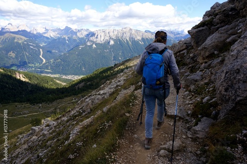 Wanderin alleine unterwegs mit Rucksack und Stecken in den Bergen / Aussicht auf Dolomiten Gipfel