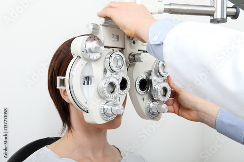 woman doing eyesight measurement with optical phoropter photo