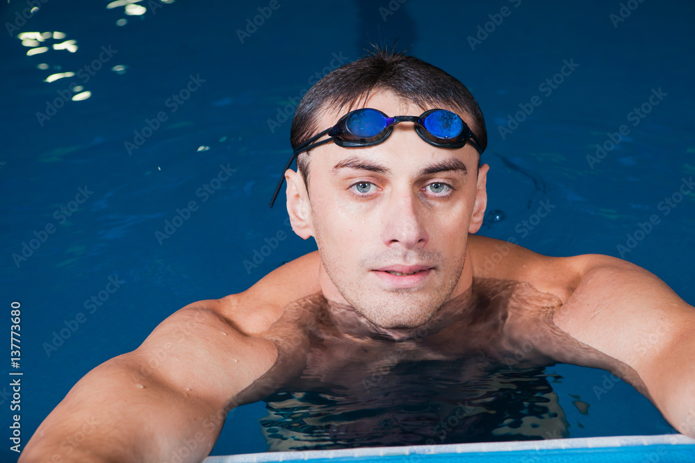 Portrait of a fit swimmer and goggles in pool at fitness center