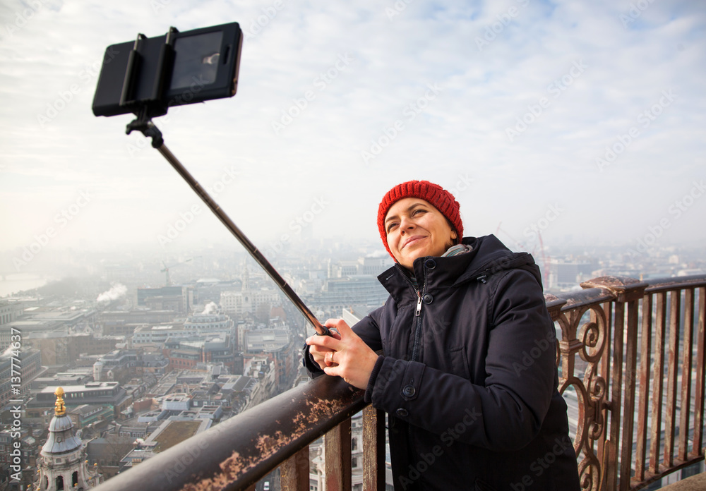 Obraz premium woman taking a selfie from the rooftop of St Paul's Cathedral on a foggy day in London - city break - tourism concept