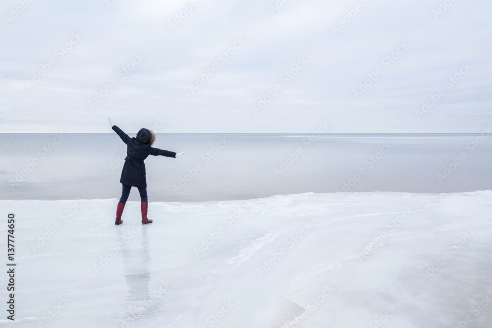 Young woman on the ice at the seashore feels the freedom in winter afternoon. Young woman on the ice at the seashore feels the freedom in winter afternoon.