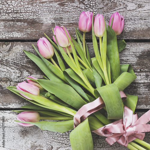 Bouquet of pink tulips on a shabby wooden table.