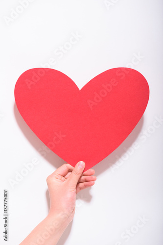 Valentines day and love concept.Hand holding a red heart shape card on white background.