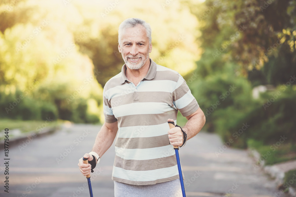 Obraz premium Joyful pleasant man using poles