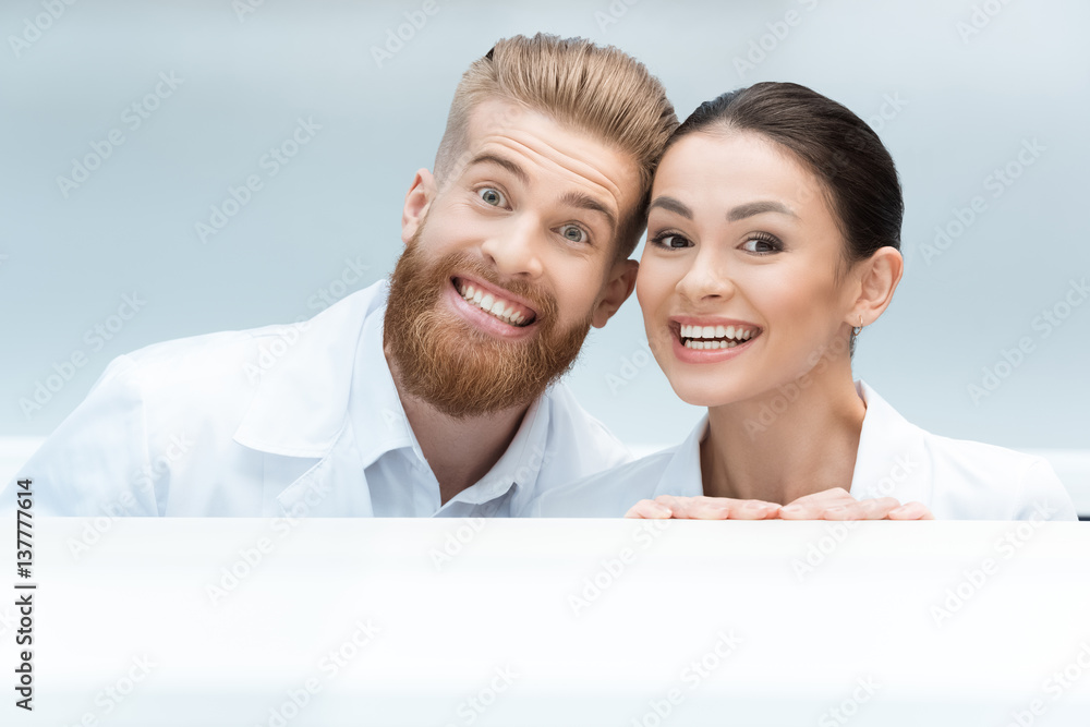 portrait of smiling scientists looking out behind table in lab portrait of smiling scientists looking out behind table in lab