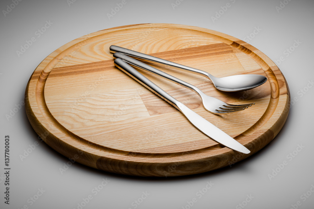 spoon fork and knife on a wooden plate spoon fork and knife on a wooden plate