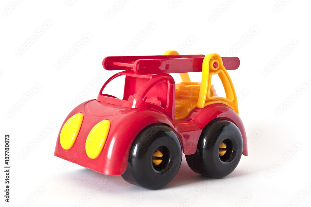 Red toy firetruck, toy car on white background, toys for intellectual development and roleplays Red toy firetruck, toy car on white background, toys for intellectual development and roleplays