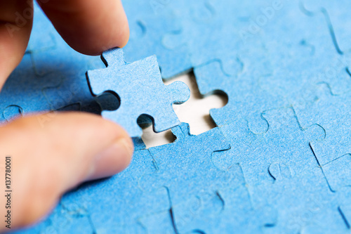 Fotografie mission complete concept - hand placing last piece of jigsaw puzzle