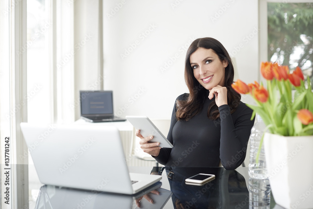 Working from home. Shot of a careworn businesswoman using her digital tablet while sitting in home office. Working from home. Shot of a careworn businesswoman using her digital tablet while sitting in home office.