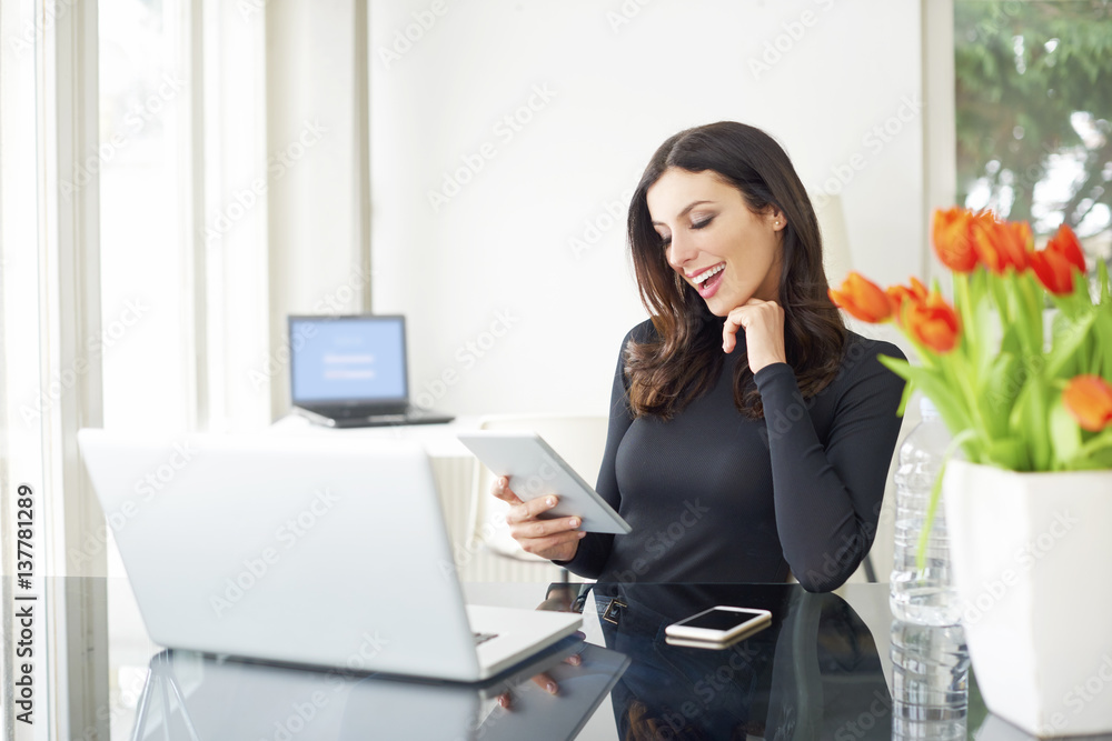Working from home. Shot of a careworn businesswoman using her digital tablet while sitting in home office. Working from home. Shot of a careworn businesswoman using her digital tablet while sitting in home office.