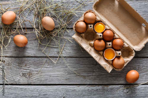 Fresh brown eggs in carton on rustic wood background