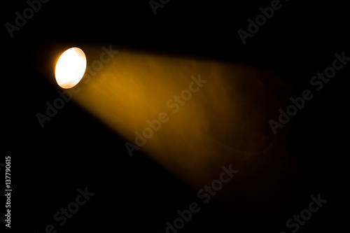 Obraz na płótnie Authentic beam of light from reflector in theatre, smoke colored on yellow, orange and red colours. w salonie