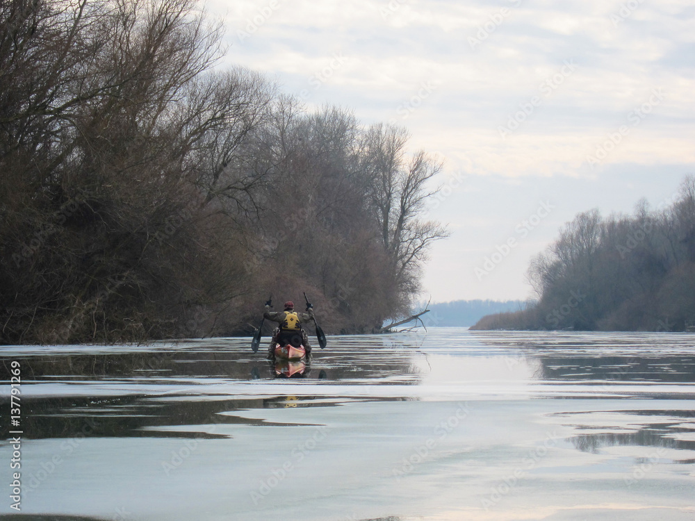 Man in red kayak on river is covered with ice. Winter kayaking on the river Danube. Winter kayaking on Danube river.