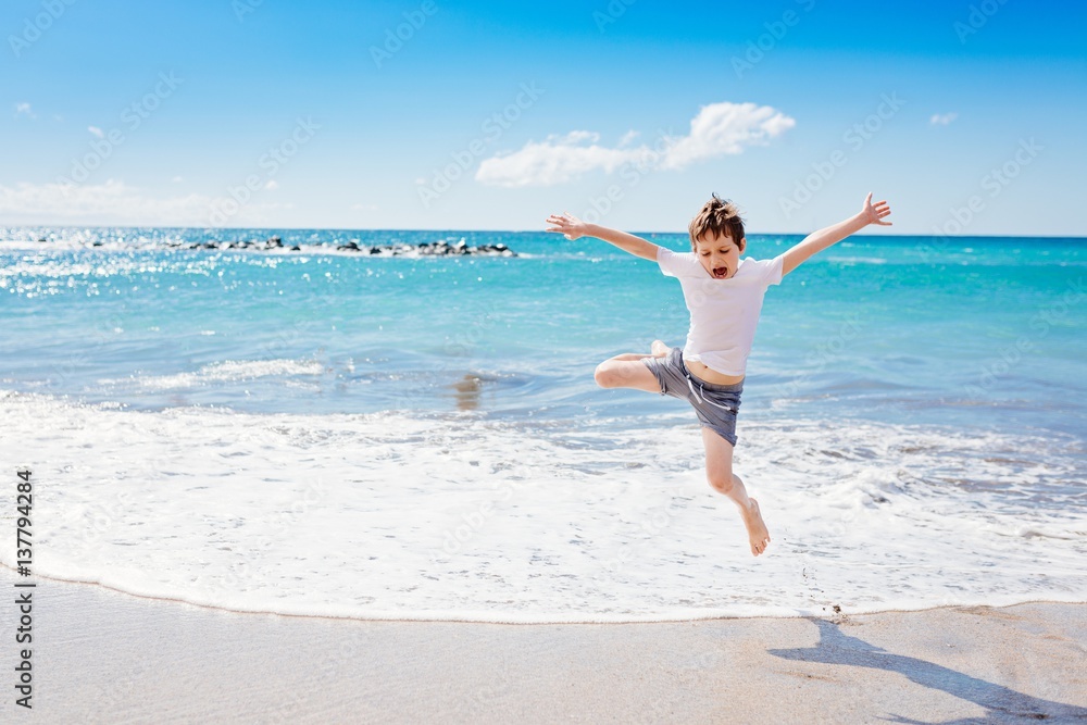 Happy 7 years boy jumping on the beach