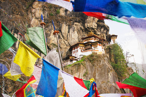 Paro Taktsang Monastery, well known as a Tiger Nest, located on the cliff side of a mountain, visible through buddhist praying flags, in Paro Valley, Himalaya, Bhutan, Asia