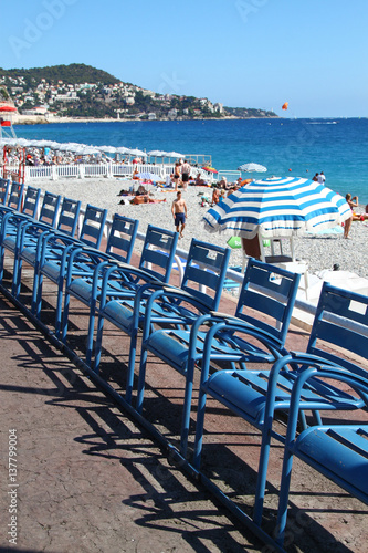 View of row of chairs and umbrellas on beach in Nice city in South France, French riviera