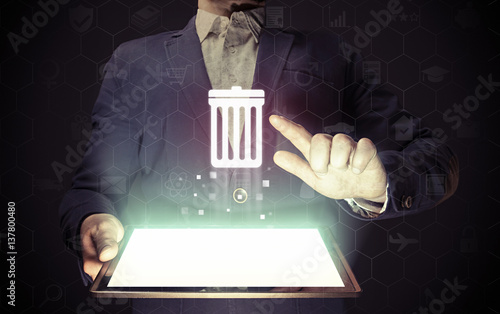 Image of a manl with tablet in his hands. He presses trash can icon. The concept of deleting files, contacts, putting in order, cleaning service etc