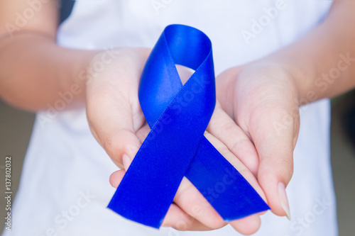 Dark blue ribbon on woman hand, Satin fabric silk ribbon symboli photo