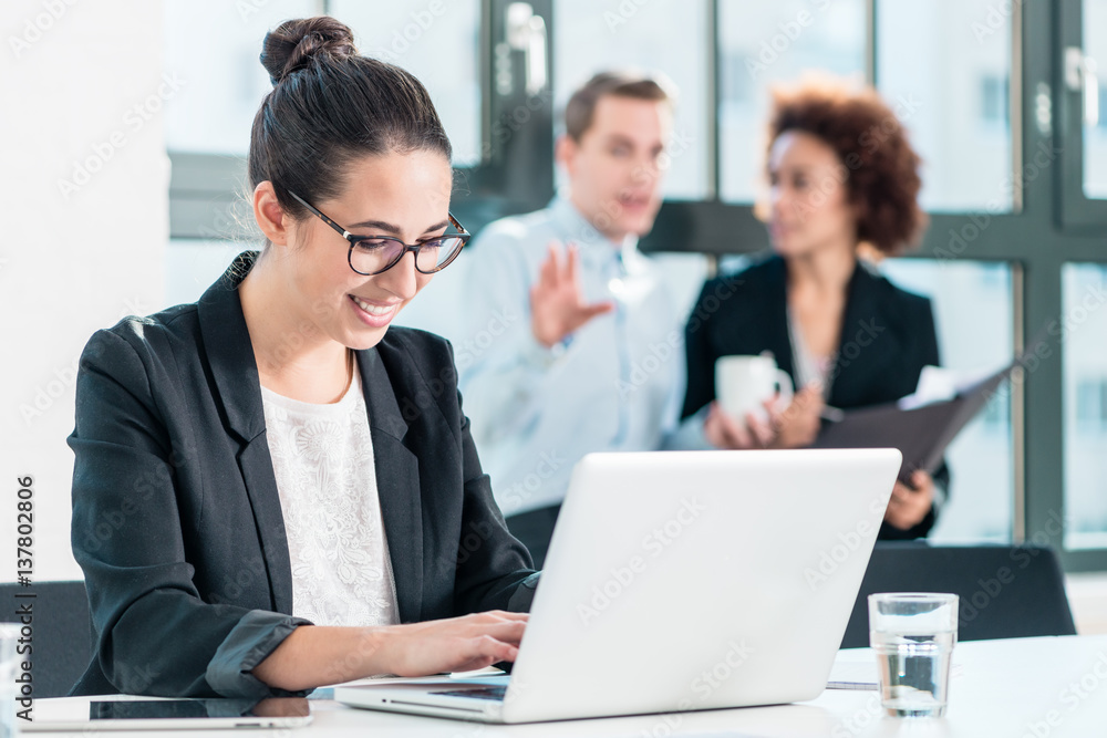 Young woman smiling while using a laptop in the office Young woman smiling while using a laptop in the office