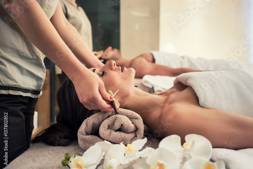 Relaxed woman lying down on massage bed during facial treatment
